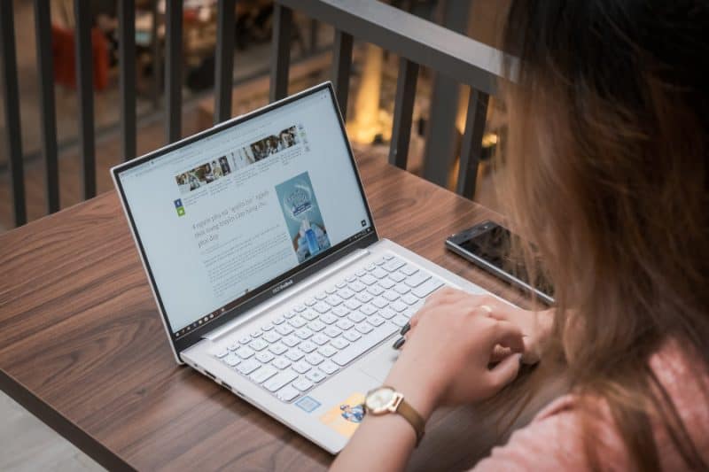 Laptop on a desk and a woman sitting in front of it